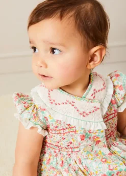 Pepa London Clementine Floral Hand Smocked Double Breasted Short Sleeve Romper in Coral (6mths-3yrs) | Clementine Floral Hand Smocked Bonnet in Coral (S-M) | Openwork Cotton Cardigan in Cream (6mths-10yrs) | Leather Mary Jane Pram Shoes in Ivory (17-20EU) | Openwork short socks White (0mths-8yrs)