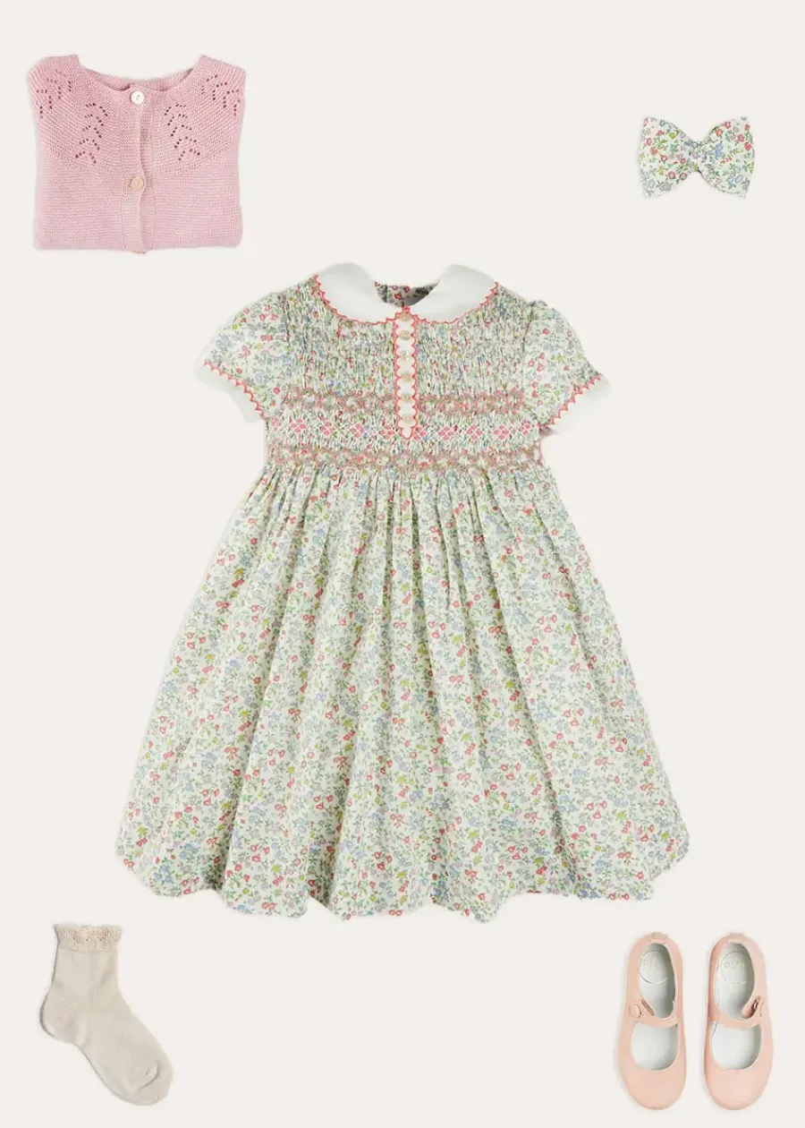 Pepa London Cordelia Floral Hand-Smocked Short Sleeve Dress in Pink Made with Liberty Fabric (12m-6yrs) | Openwork Cotton Cardigan in Pink (6mths-10yrs) | Leather Mary Jane Shoes in Pink (24-34EU) | Cordelia Floral Medium Bow Clip in Pink Made with Liberty Fabric | Celebration Short Socks with ruffle - Sand (0mths-10yrs)