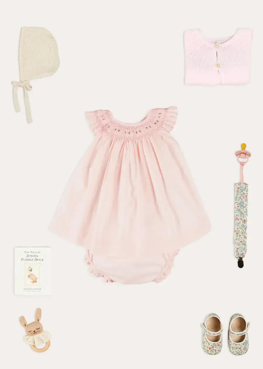Pepa London Hand Smocked Sleeveless Dress With Bloomers in Pink (1-12mths) | Openwork Detail Baby Cardigan in Pink (1-12mths) | Openwork Knitted Bonnet in Beige(S-L) | Cordelia Liberty Floral Mary Jane Pram Shoes in Pink (17-20EU) | Cordelia Liberty Floral Dummy Clip in Pink | Knitted Bunny Teether in Beige | BIBS Dummy in Pink