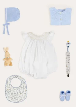 Pepa London Hand Smocked Sleeveless Romper in White (3-18mths) | Openwork Detail Baby Cardigan in Blue (1-12mths) | Lace Detail Knitted Bonnet in Blue (1-6mths) | Ellis Rounded Bib with Embroidery in Blue Made with Liberty Fabric | Lace Detail Knitted Booties in Blue | Ellis Dummy Clip in Blue Made with Liberty Fabric | My First Bunny in a Box - Blue | BIBS Dummy in Blue