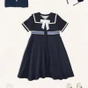 Pepa London Mariner Collar Bow Detail Short Sleeve Dress in Navy (4-12yrs) | Plain Cardigan in Navy (6mths-10yrs) | Girls Ivory Leather Mary Jane Shoes (20-34EU) | Navy Linen Big Bow Hairband | Cotton Short Socks Cream (0mths-10yrs)