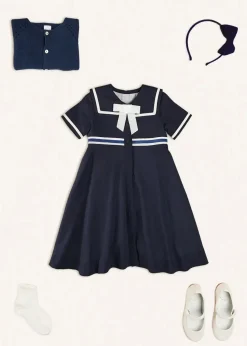 Pepa London Mariner Collar Bow Detail Short Sleeve Dress in Navy (4-12yrs) | Plain Cardigan in Navy (6mths-10yrs) | Girls Ivory Leather Mary Jane Shoes (20-34EU) | Navy Linen Big Bow Hairband | Cotton Short Socks Cream (0mths-10yrs)