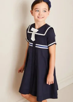 Pepa London Mariner Collar Bow Detail Short Sleeve Dress in Navy (4-12yrs) | Plain Cardigan in Navy (6mths-10yrs) | Girls Ivory Leather Mary Jane Shoes (20-34EU) | Navy Linen Big Bow Hairband | Cotton Short Socks Cream (0mths-10yrs)