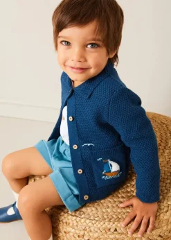 BOY Pepa London Nautical Boat Embroidery Polo Collar Cardigan in Blue (12mths-6yrs) | Chesham Striped Mao Collar Long Sleeve Shirt in Red (3-10yrs) | Plain Elasticated Shorts in Blue (12mths-4yrs) | T-Bar Baby Shoes in Blue (20-26EU) | Ribbed Short Socks in Beige (0mths-10yrs)